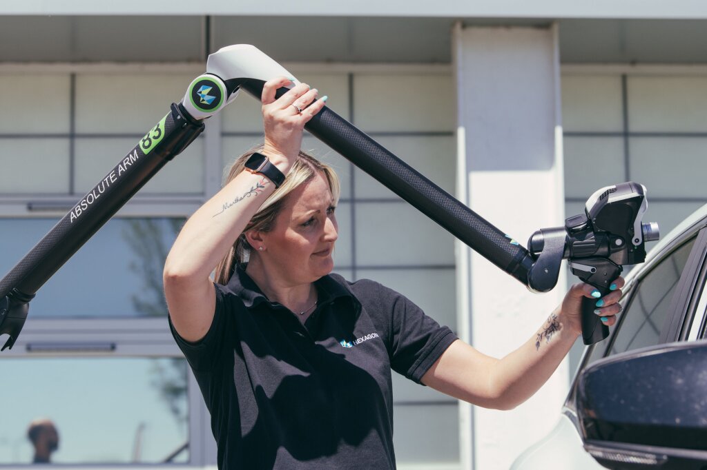A woman fixing a robotic arm onto a car.